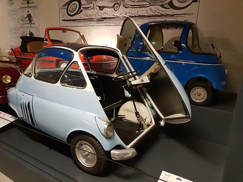 Pale blue and white bubble car with its whole front swung open, the steering column moving out with it. Opens a larger view