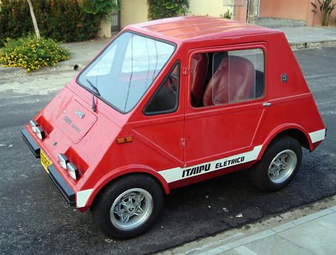 A small red angular car with a large flat windscreen, square headlamps and a white ITAIPU ELÉTRICO sill stripe. Opens a larger view