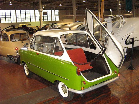 Lime green and white small car from behind, its rear door raised over a red rear-facing seat.