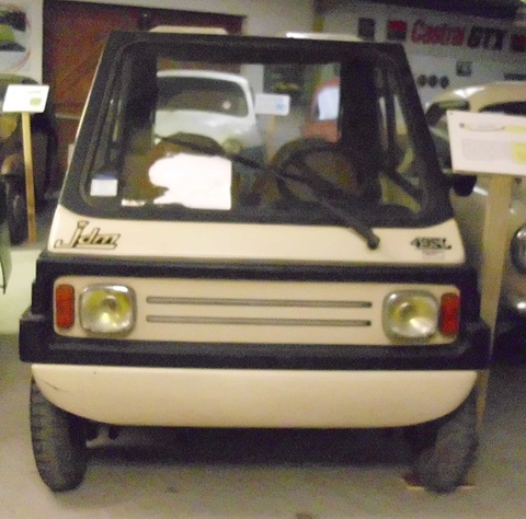 Front of a small boxy cream car with black trim, two round headlamps, a slatted grille and 49SL badge on the scuttle.
