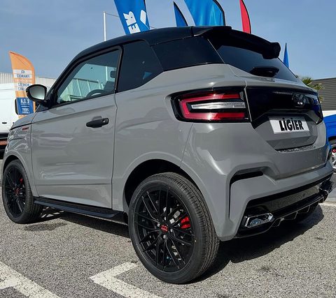 Rear three-quarter of a grey small car with a black roof and spoiler, LED tail lamps and black alloy wheels with red calipers. Opens a larger view