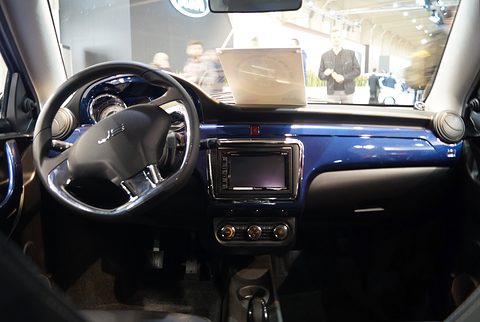 Car interior with a two-spoke steering wheel, a central touch screen and a glossy dark blue dashboard insert. Opens a larger view