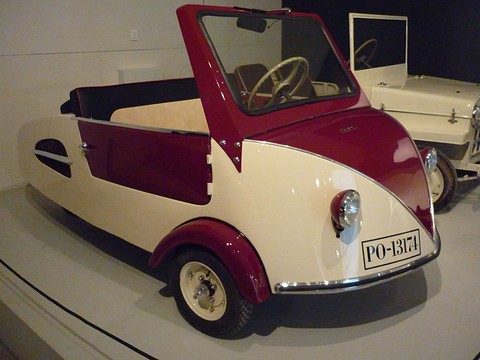 Maroon and cream open microcar with a V-shaped two-tone nose, a single headlamp each side and a tall windscreen. Opens a larger view
