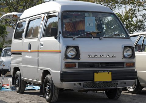 Silver high-roof van seen from the front with an orange stripe and a card in the windscreen. Opens a larger view