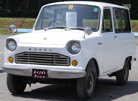 White small van with a bonnet, round headlamps and a MAZDA B360 plate, seen from the front. Opens a larger view