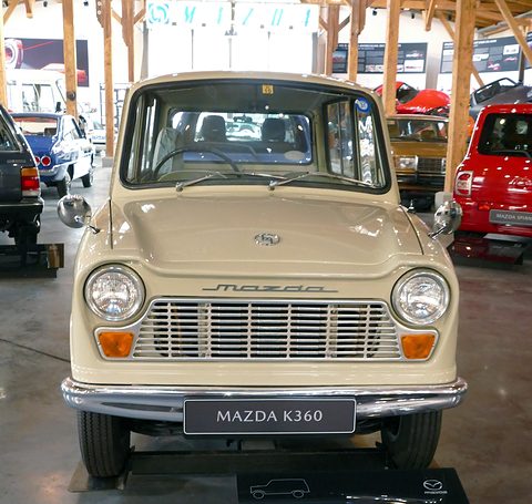 Beige small van seen from the front with a slatted grille and a MAZDA K360 plate. Opens a larger view