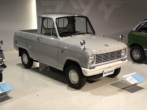 Grey small pickup with a white cab roof on a polished white floor. Opens a larger view
