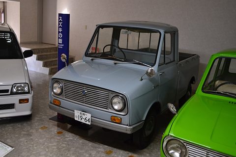 Pale blue small pickup with a slatted grille between a white car and a green car. Opens a larger view
