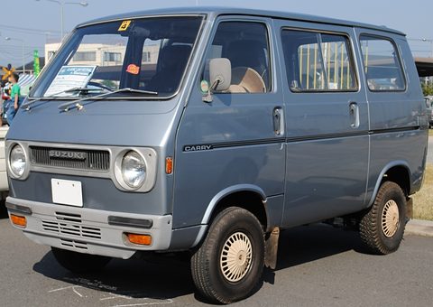 Blue-grey cab-over van with a display card on its windscreen. Opens a larger view