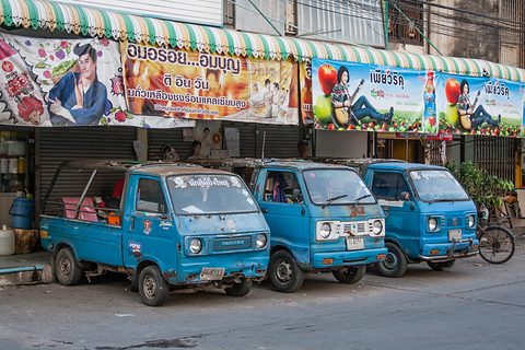 Three blue cab-over taxis parked in a row under colourful shop signs. Opens a larger view