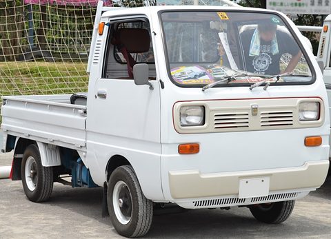 White cab-over pickup with a cream grille panel, someone sitting in the cab. Opens a larger view