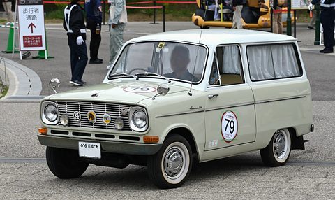Pale green small estate van with a 79 roundel on its door and curtains in the windows. Opens a larger view