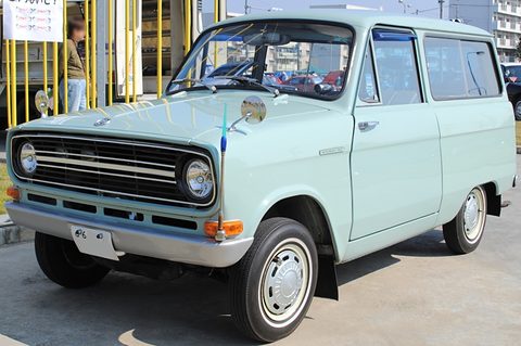 Pale green small estate van with a long grille, yellow scaffolding behind. Opens a larger view
