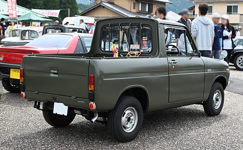 Rear three-quarter of a dark grey-green pickup with a rack behind its cab. Opens a larger view
