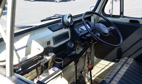 Inside a truck cab: a black dished wheel, a cream dashboard and a black seat. Opens a larger view