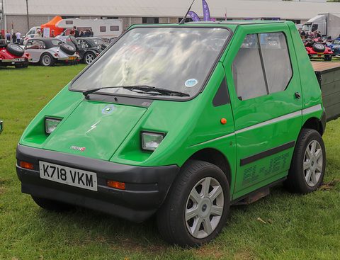 Bright green angular two-seat microcar with EL-JET lettering on its door and a UK plate on grass. Opens a larger view