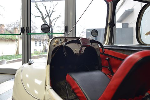 Handlebar steering and red-trimmed seats inside an open cream tandem body.