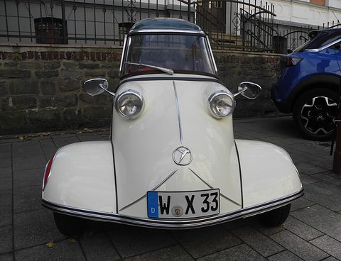 White bubble car head-on with mirrors and a Messerschmitt badge, registration W-X 33. Opens a larger view