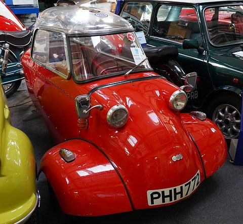 Red bubble car with clear canopy facing the camera in a show hall. Opens a larger view