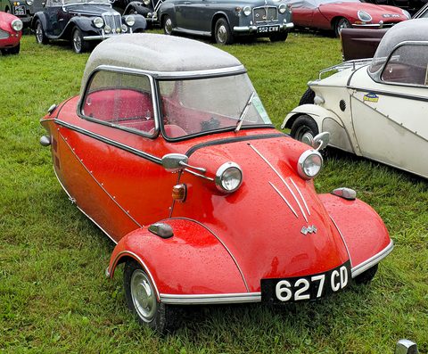 A red KR200 seen from the front three-quarters on grass, its pale canopy closed and an English number plate below the nose. Opens a larger view