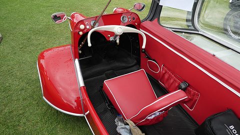 The interior of a red 1961 KR200 with the canopy open: a red front seat, the steering bar and the floor pedals. Opens a larger view