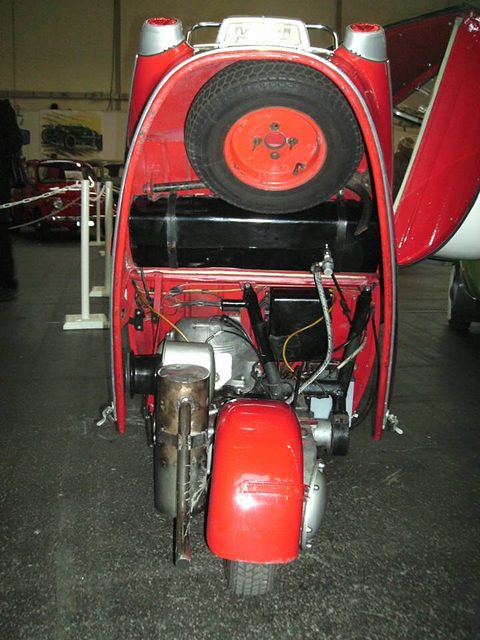 Red tail section lifted to reveal the single-cylinder engine and a spare wheel on its inside. Opens a larger view