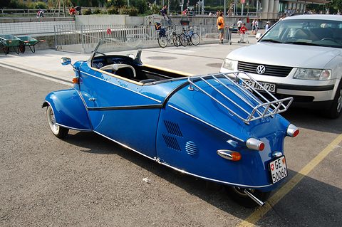 Blue tapering tail with a chrome rack and Geneva registration plate in a car park. Opens a larger view