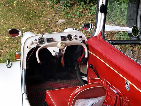White dashboard and cream handlebar above red carpets and a red-trimmed seat. Opens a larger view