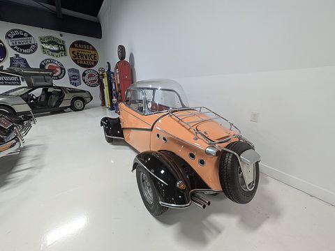 Orange and black tail with a spare wheel on the chrome rack, enamel signs on the wall. Opens a larger view