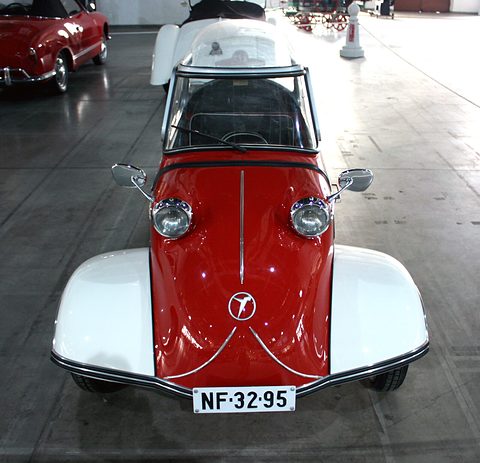 Red bubble car with white wings and registration NF-32-95 on a grey hall floor. Opens a larger view