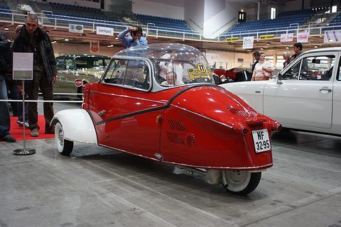 A red and white KR200 from the rear three-quarters on a show floor, showing the tapering tail and its cooling louvres. Opens a larger view