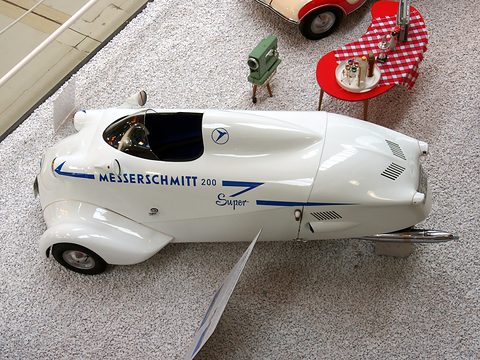Top view of a white streamlined car with one small open cockpit and a short windscreen. Opens a larger view