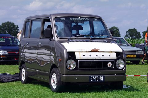 Tall grey boxy small van with a short nose, round headlamps, a white bonnet panel and Honda lettering, parked on grass at a show. Opens a larger view
