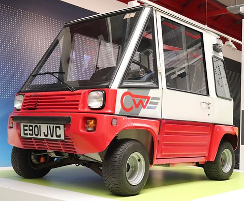 Red and white boxy car with square headlamps, a CW logo on the door and plate E901 JVC on a green plinth. Opens a larger view