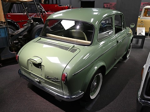 Rear three-quarter of a pale green small saloon with rows of cooling slots in its engine lid. Opens a larger view