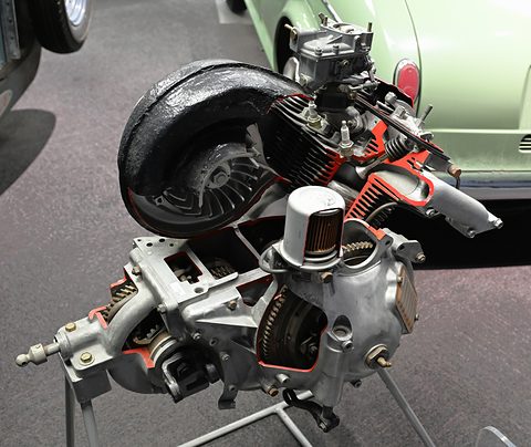 Cut-away small engine on a stand, its fan housing, cylinders and red-painted section faces exposed.