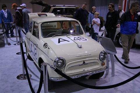 Cream rounded small saloon seen head-on behind rope barriers, a large A48 number on the bonnet, visitors behind. Opens a larger view