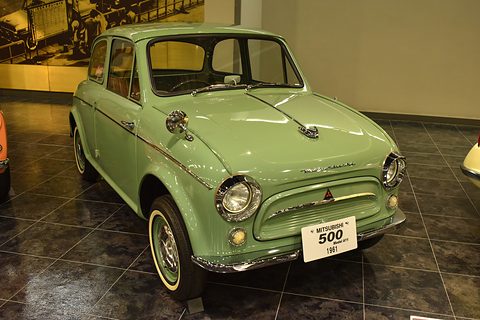 Pale green small saloon with whitewall tyres and a Mitsubishi 500 sign on its bumper, on a tiled floor. Opens a larger view