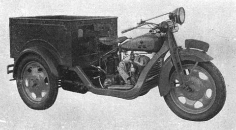 Black and white side view of a three-wheeled truck: motorcycle front with headlamp and saddle, open box over two rear wheels.