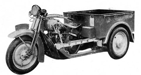 Black and white view of a three-wheeled light truck from the front left, motorcycle forks and an open steel cargo box. Opens a larger view