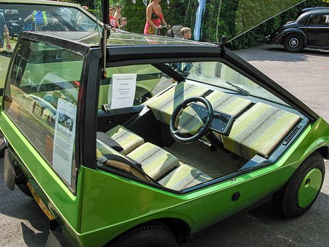 Green concept car with its glass roof panel raised, three striped seats across the cabin. Opens a larger view