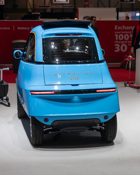 Rear of a light-blue bubble car with Lite script and a tail-light strip, on a white show floor. Opens a larger view