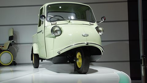 Low front view of a pale green three-wheeled truck with two headlamps, a chrome bumper bar and one front wheel. Opens a larger view