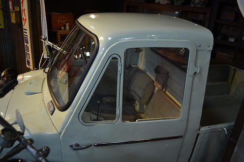 Close view of a pale green truck cab with a quarter-light, a wind-up side window and a chrome door handle. Opens a larger view
