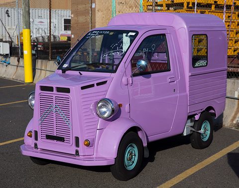 Lilac tiny van with a ribbed Citroën H-van-style nose and round headlamps in a car park. Opens a larger view