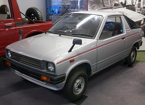 Silver small coupé-utility with a red side stripe, square headlamps and a short open bed behind the cab, in a museum.