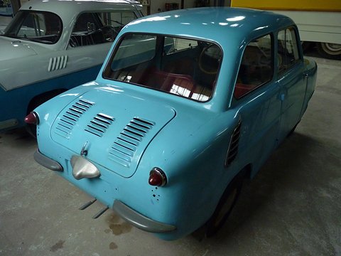Sky-blue small saloon from behind, three banks of louvres on the tail and red upholstery inside.