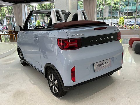 Rear of a pale blue open two-seater with white roll hoops and a Wuling tail band in a bright showroom. Opens a larger view