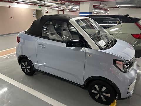 Pale blue small convertible with a black fabric roof up, parked in an underground car park. Opens a larger view