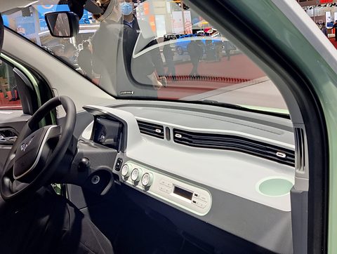 Pale green and white dashboard with a round dial pod and a steering wheel, seen through the open door. Opens a larger view